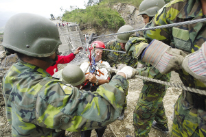 13日，臺灣高雄縣六龜鄉(xiāng)新開村有20多戶遭泥石流淹沒。圖為軍人正陸續(xù)將生還者救出。