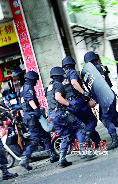 特警將嫌疑人（紅圈內(nèi)）押上警車。